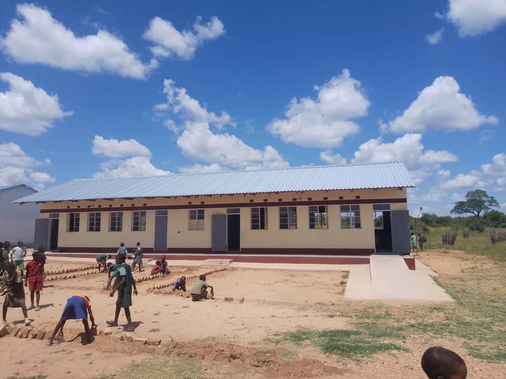 A completed school building with learners outside